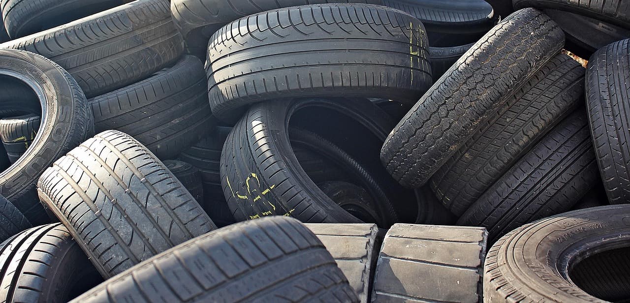 A heap of used car tyres, tread facing out, in low sun