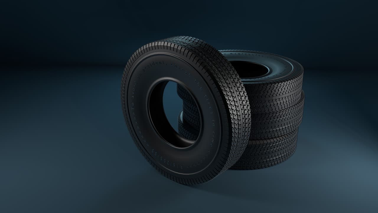 Two car tyres, one stood on its tread against the other, on a dark ground